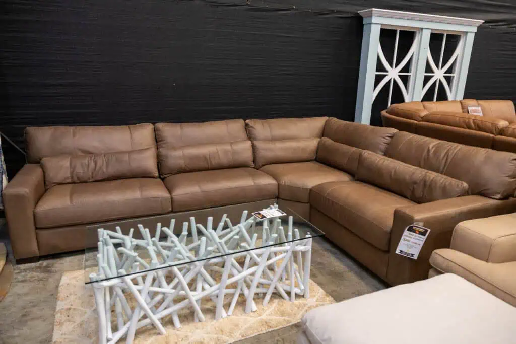 Large brown sectional sofa with a glass coffee table in front.