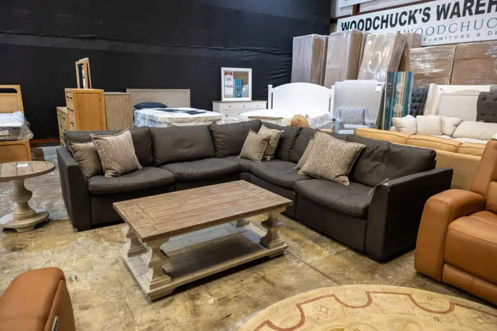 Black sectional sofa with beige and brown pillows in furniture store.