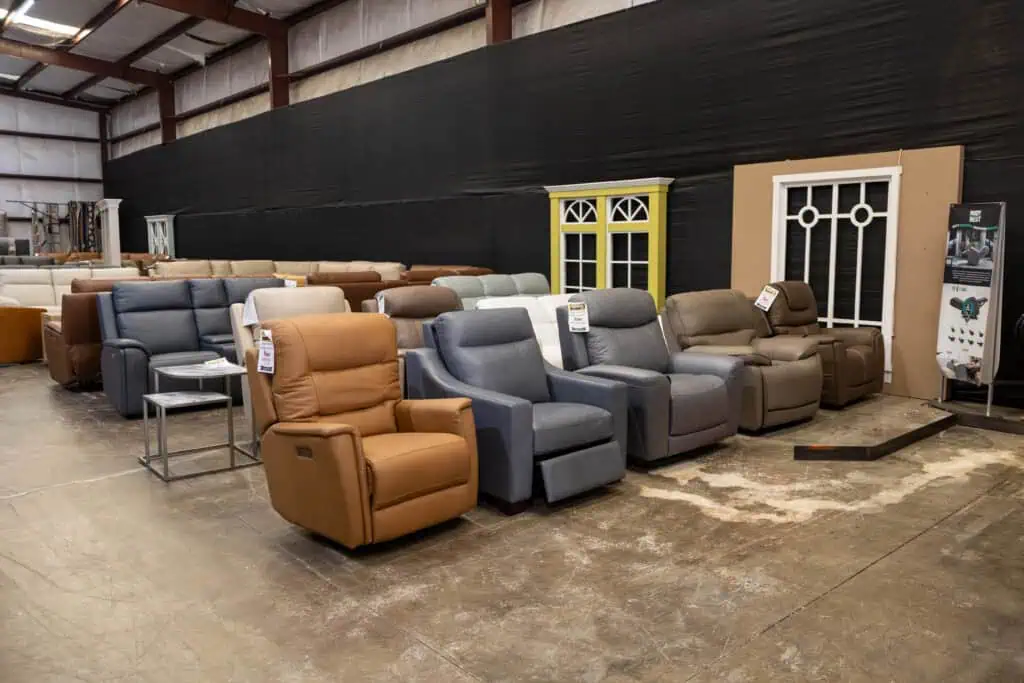 Various recliner chairs and small tables in a warehouse setting.