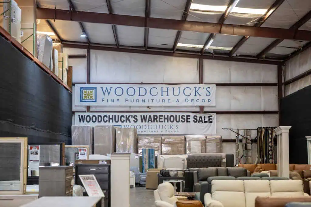Interior of a warehouse with furniture and signs for Woodchuck's Warehouse Sale.