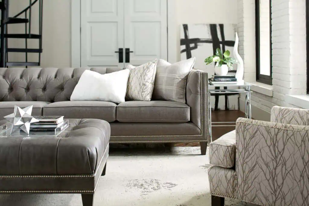 A stylish living room featuring a plush gray sofa, patterned armchair, and contemporary decor, showcasing versatile furniture that adapts to evolving home designs.