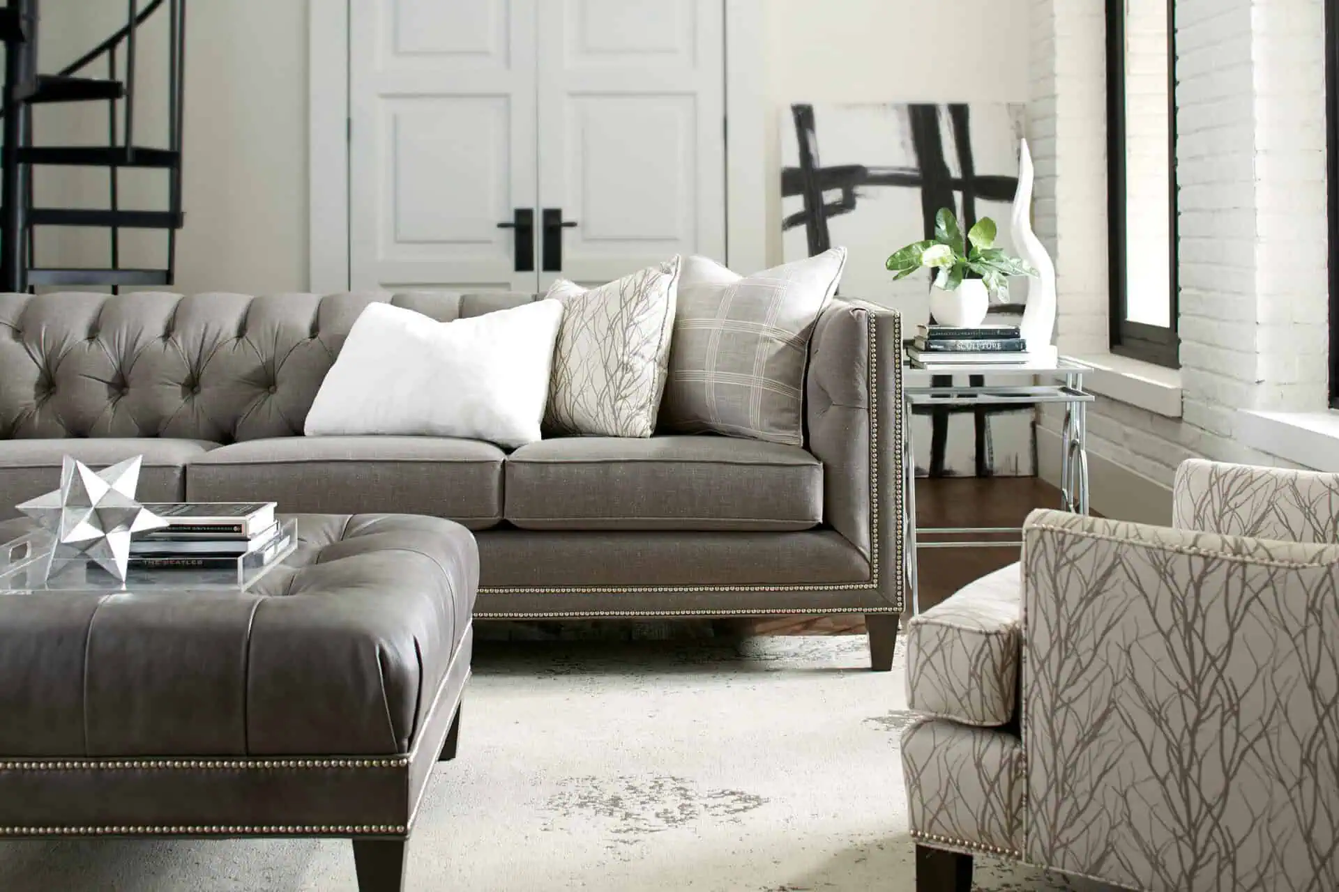 A stylish living room featuring a plush gray sofa, patterned armchair, and contemporary decor, showcasing versatile furniture that adapts to evolving home designs.