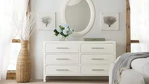 A light colored bedroom dresser and mirror