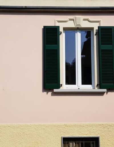 Finestra con infissi in PVC e persiane in legno verde chiaro.