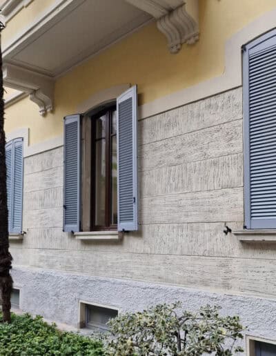 Finestre con persiane in alluminio grigio su edificio storico, sicurezza e stile elegante.