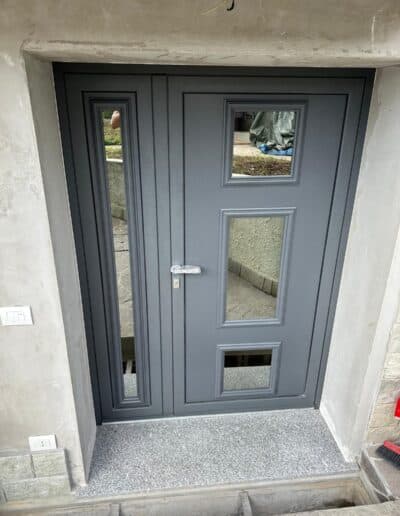 Finestra e porta in alluminio grigio con vetri decorativi, installate da ZCM Serramenti.