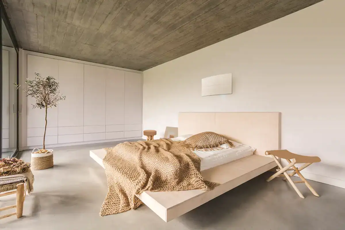 Luminosa camera da letto con arredi moderni e minimalisti, letto in stile scandinavo con coperte a maglia.