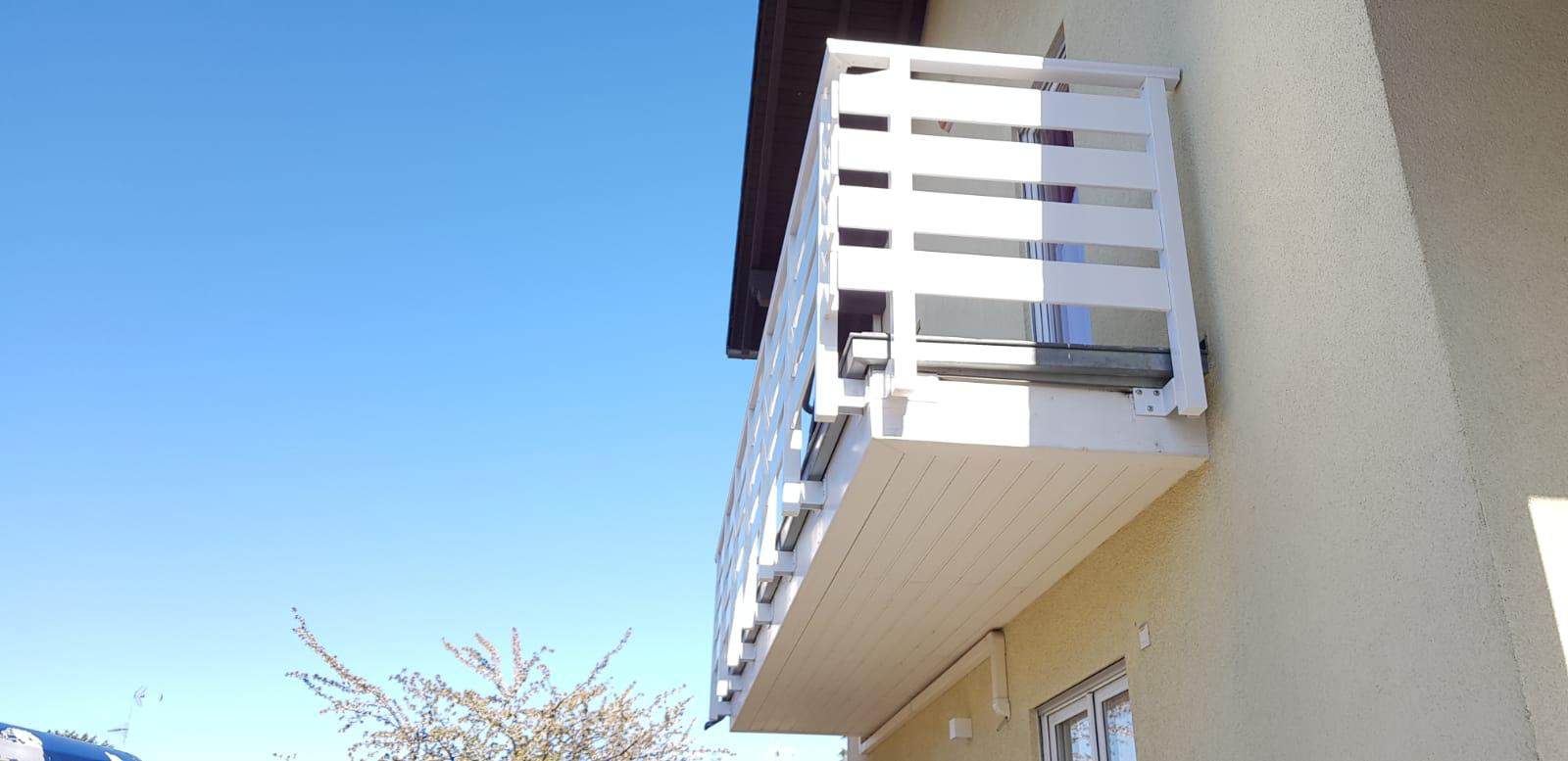 Balcone in alluminio bianco con ringhiera in legno, installato su facciata di edificio residenziale.