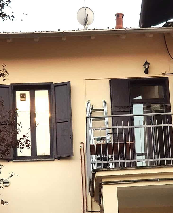 Finestra con persiane in legno verniciato nero e porta finestra nella facciata di un edificio residenziale.