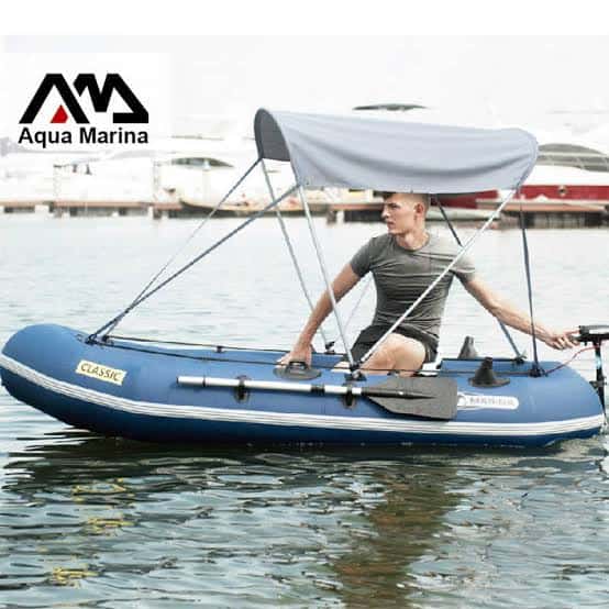 Man relaxing on inflatable boat with Aqua Marina canopy on water.