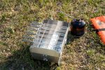Portable Skotti Pikes camping stove with multiple burners on grassy terrain.
