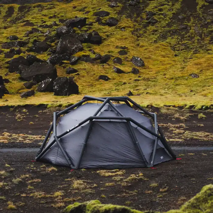 Portable shelter in rugged outdoor landscape with moss-covered terrain.