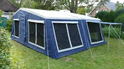 Large trailer tent with extended awning for outdoor camping comfort.