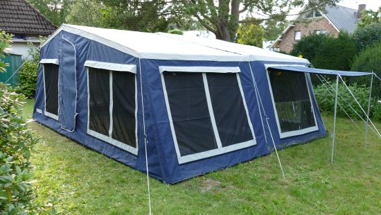 Large trailer tent with extended awning for outdoor camping comfort.