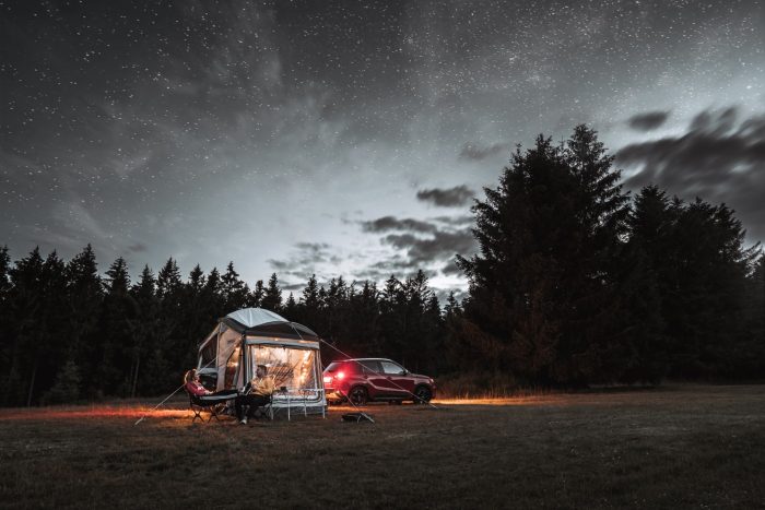 Off-road trailer with family tent under starry night sky.