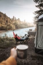 Off-road camping with family near river.