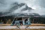 Off-road trailer with family tent in scenic mountain landscape.