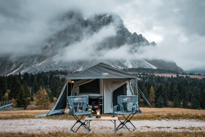Off-road trailer with family tent in scenic mountain landscape.