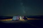 Off-road trailer with family tent under starry night sky.