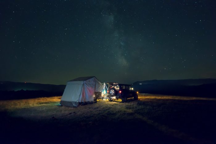 Off-road trailer with family tent under starry night sky.