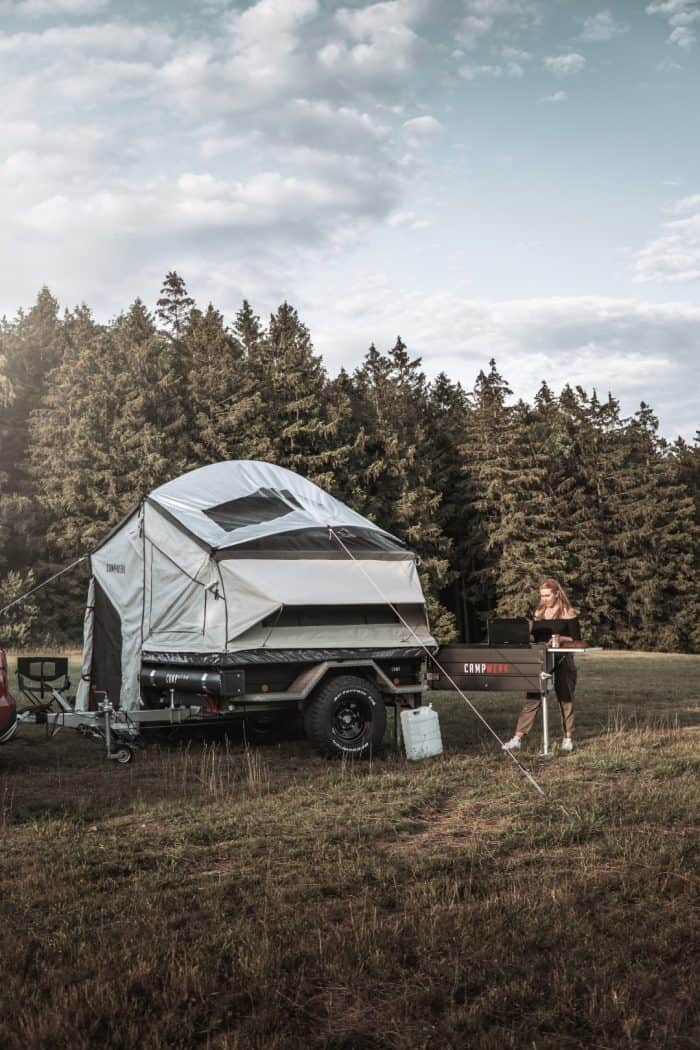 Off-road camper trailer with family tent in nature.