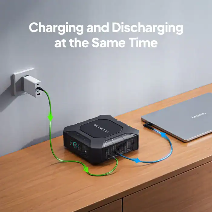 Portable power station charging and discharging simultaneously with a laptop nearby.