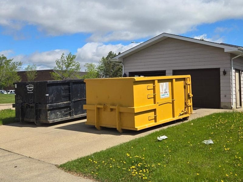 Empty dumpster containers outside a residential garage for junk removal services.