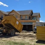 Dump truck collecting debris at a residential construction site for junk removal.