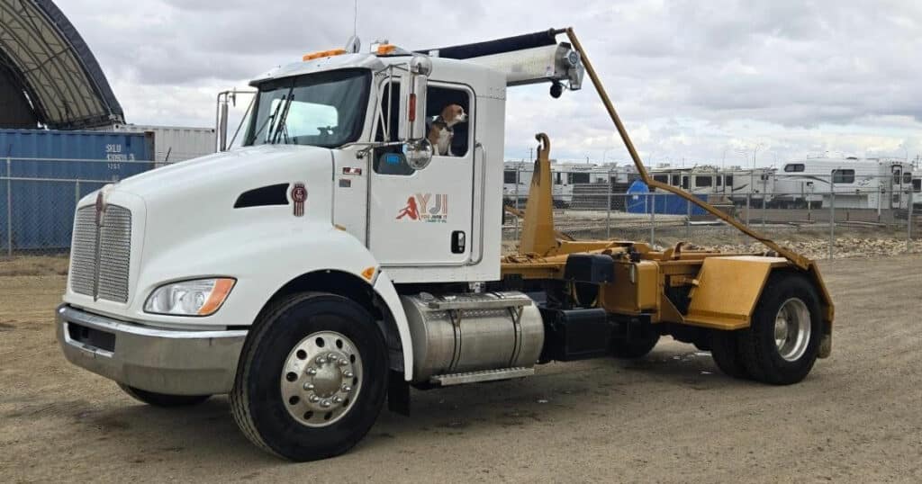 White commercial truck with a dog in the driver's seat for junk removal services.