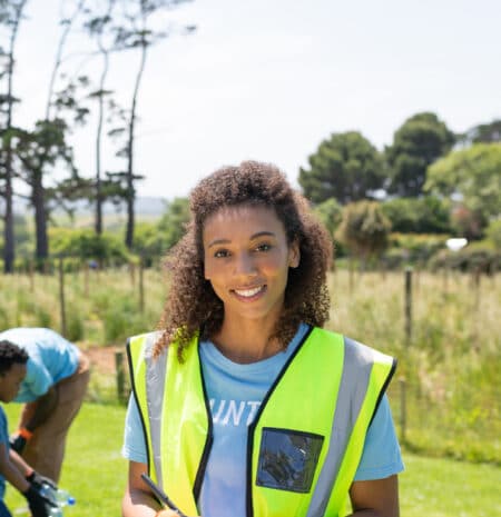 Recyclable waste collection volunteer outside with trash bag and clipboard, environmental cleanup activity.