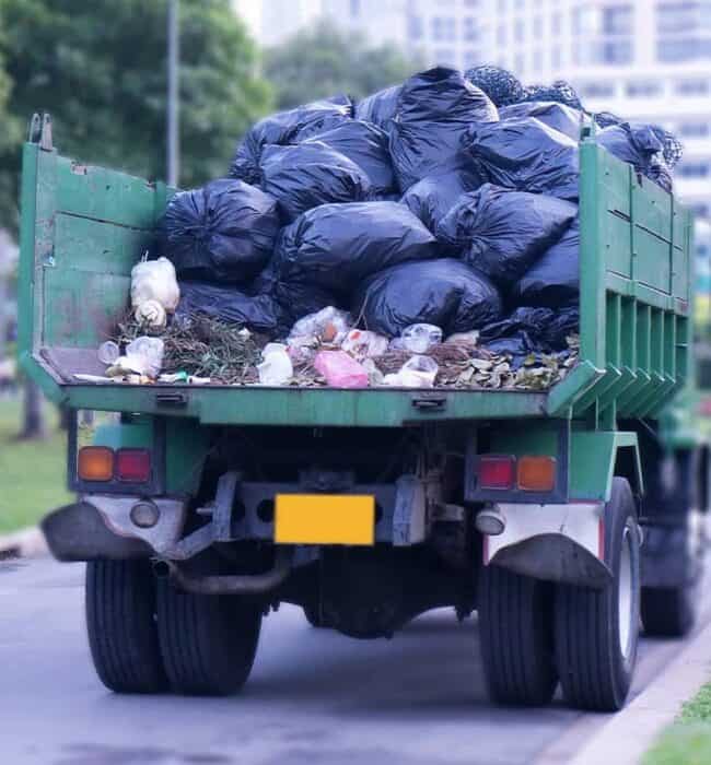 Overflowing junk truck filled with trash bags and debris, ready for disposal services.