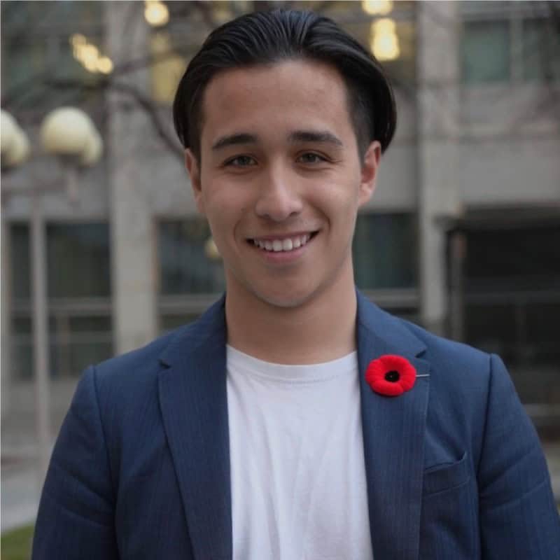 Young Canadian man wearing poppy for Remembrance Day, smiling outdoors at Resources rally.