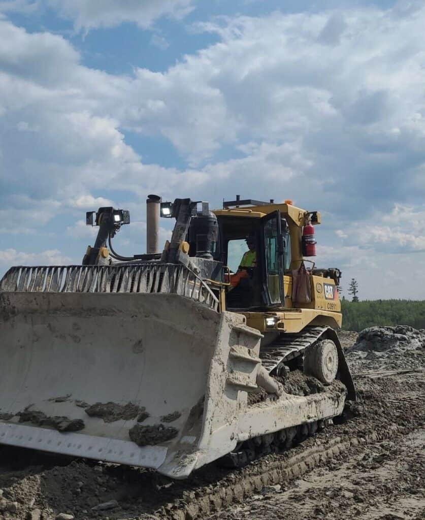Heavy-duty bulldozer working on resource extraction site in Canada.