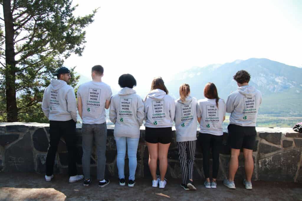 Young Canadians for Resources group wearing matching hoodies outdoors with mountain view, promoting Canadian resources and sustainable development.