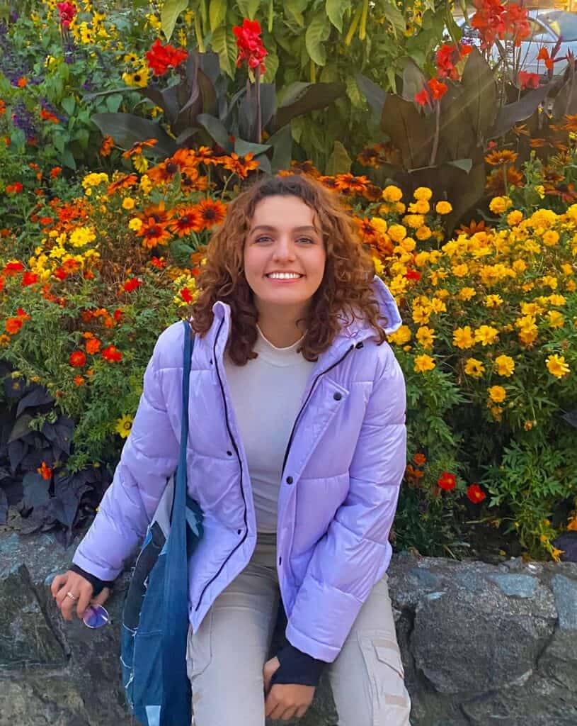 Colorful flower garden with young woman in outdoor setting, environmental education, nature appreciation, youth engagement in resource conservation.