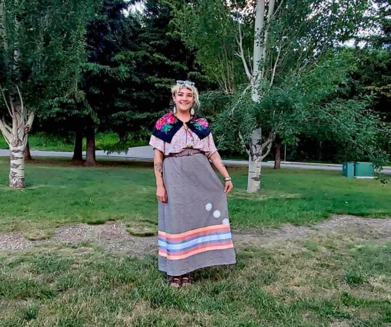 Young woman outdoors in traditional clothing at a park with trees, promoting youth involvement in resource industries.