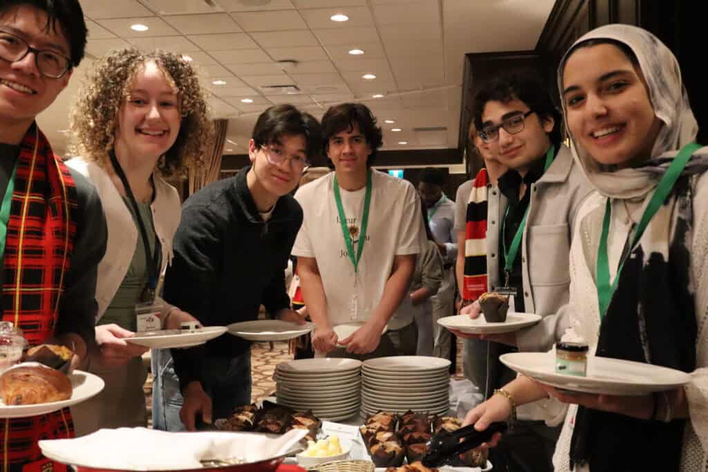 YCR young Canadian students at a networking event, enjoying baked goods and engaging with peers to promote the importance of resource development and sustainable energy solutions in Canada.