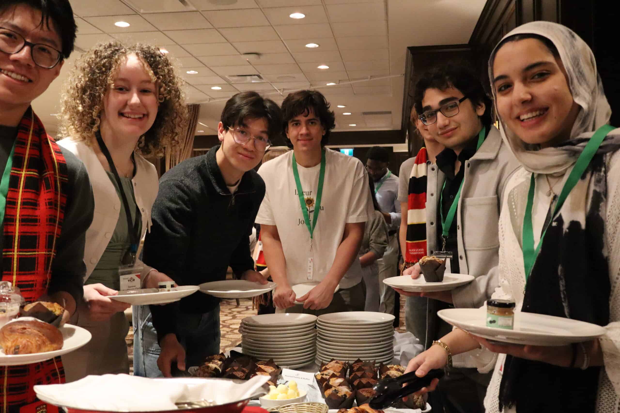 YCR young Canadian students at a networking event, enjoying baked goods and engaging with peers to promote the importance of resource development and sustainable energy solutions in Canada.