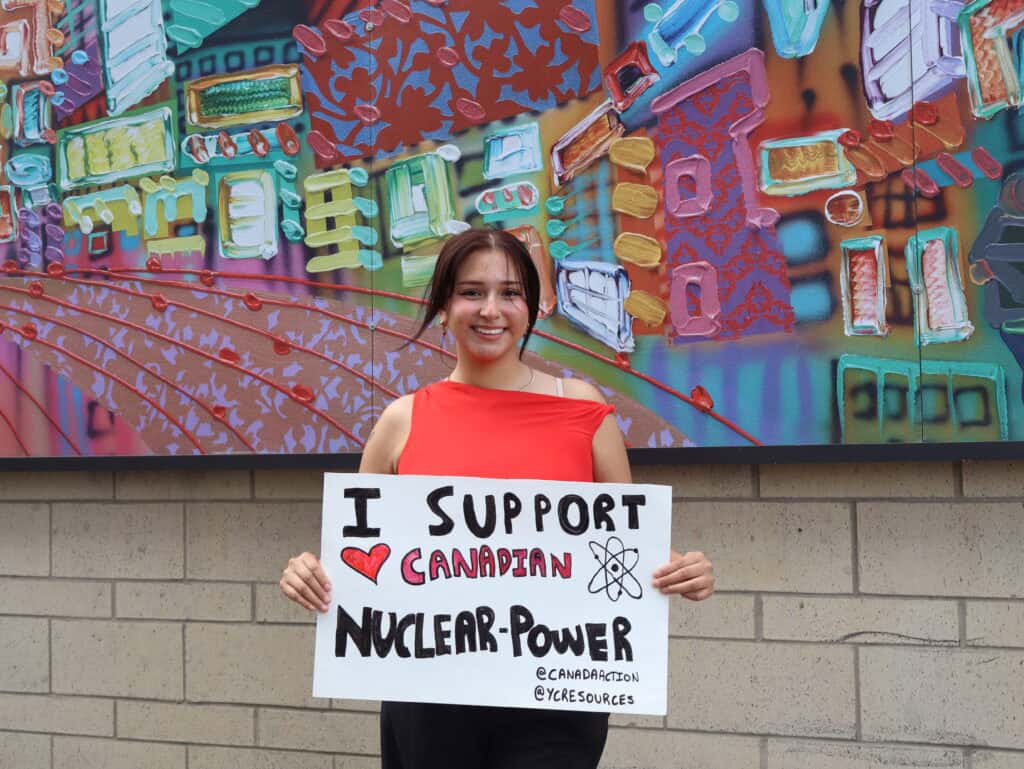 Supporting Canadian nuclear power, young woman holding sign, Young Canadians For Resources, environmental advocacy, clean energy, pro-nuclear, Canada energy future, grassroots activism, environmental conservation, nuclear energy supporters, YCR organization.