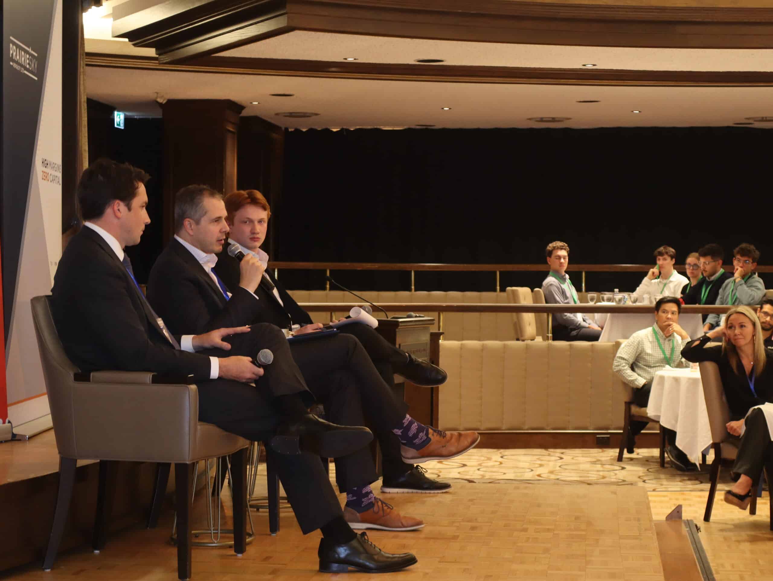 Young Canadians for Resources (YCR) panel discussion at a conference, with four panelists speaking into microphones and an audience of young professionals listening attentively in a formal setting.