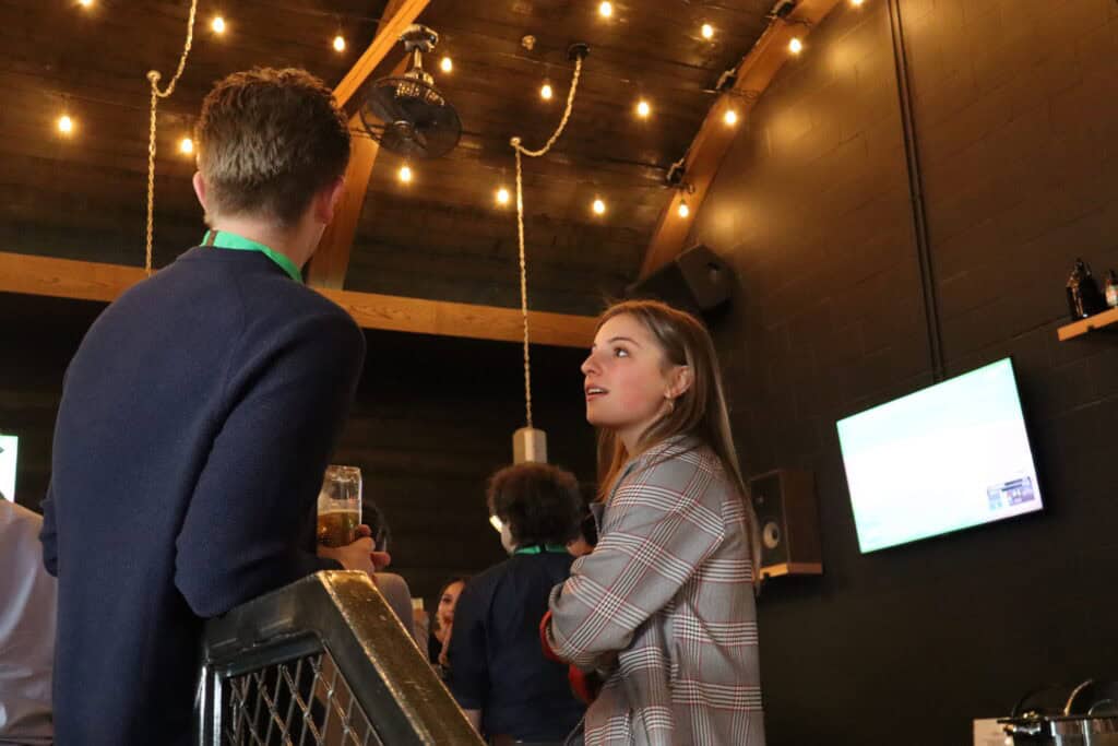 Young adults discussing music and sports at a social event.