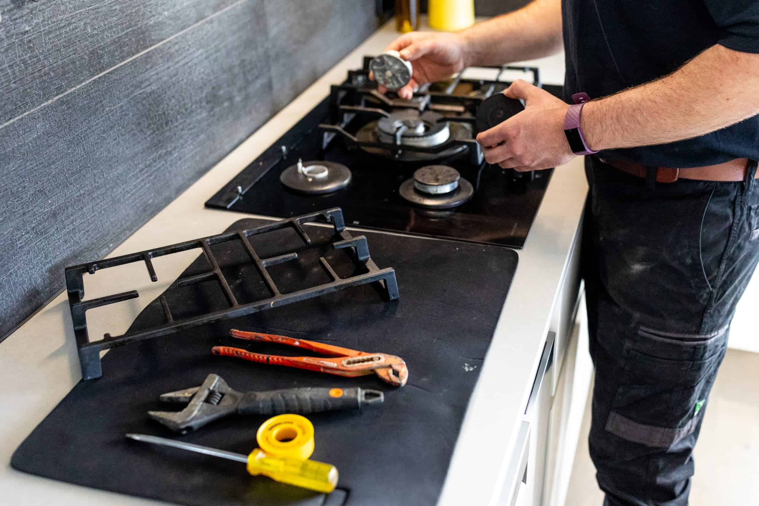 Gas plumbing technician working on stove connection.