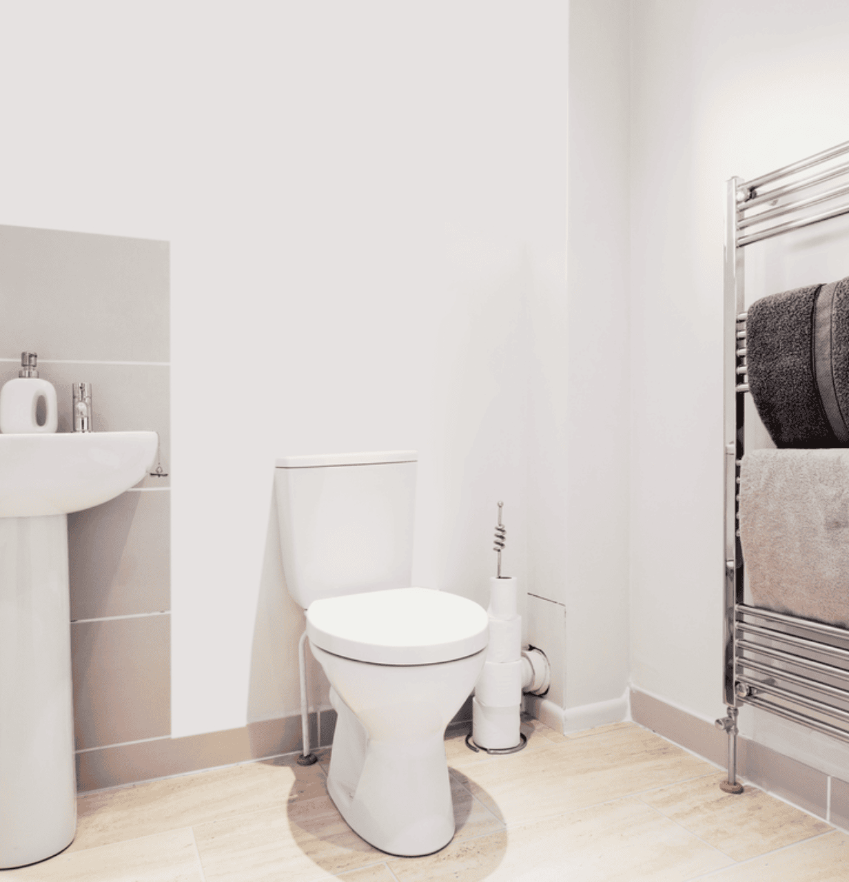 A clean, modern bathroom featuring a white toilet, a white bathtub with chrome fixtures, wood-look floor tiles, and a white vanity with a granite countertop.