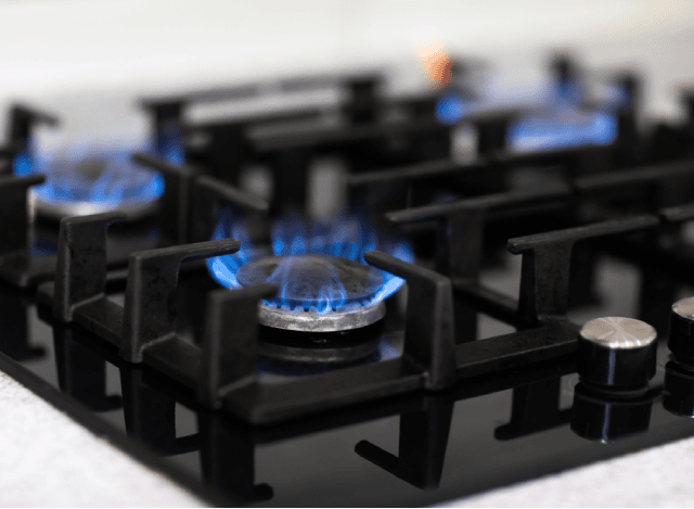 Gas cooktop with blue flames and five burners.
