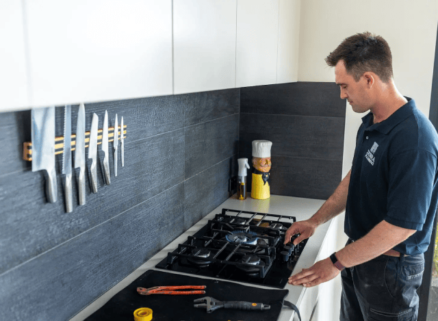 Plumber testing a gas stovetop in a modern kitchen.