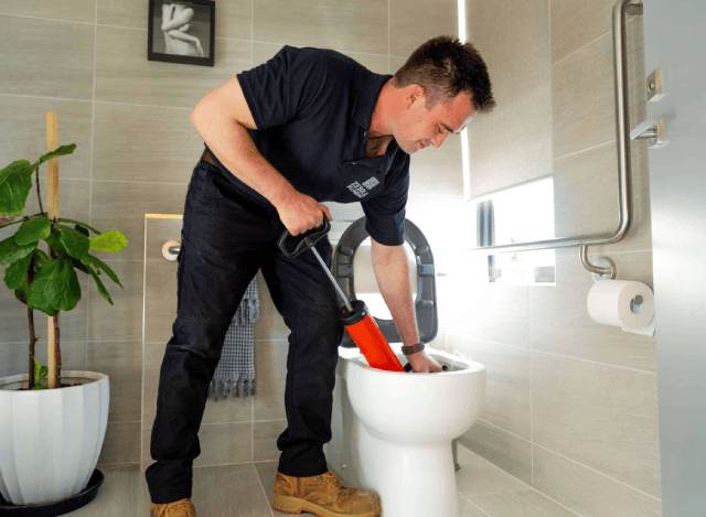 Plumber unclogging a toilet.
