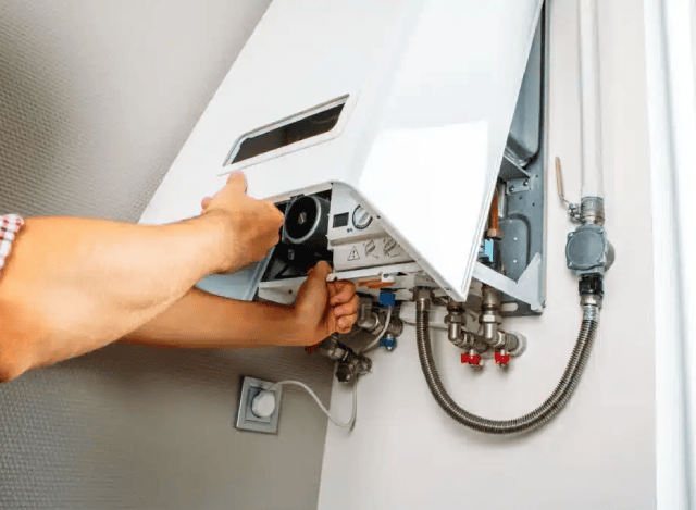 Person servicing a hot water unit.