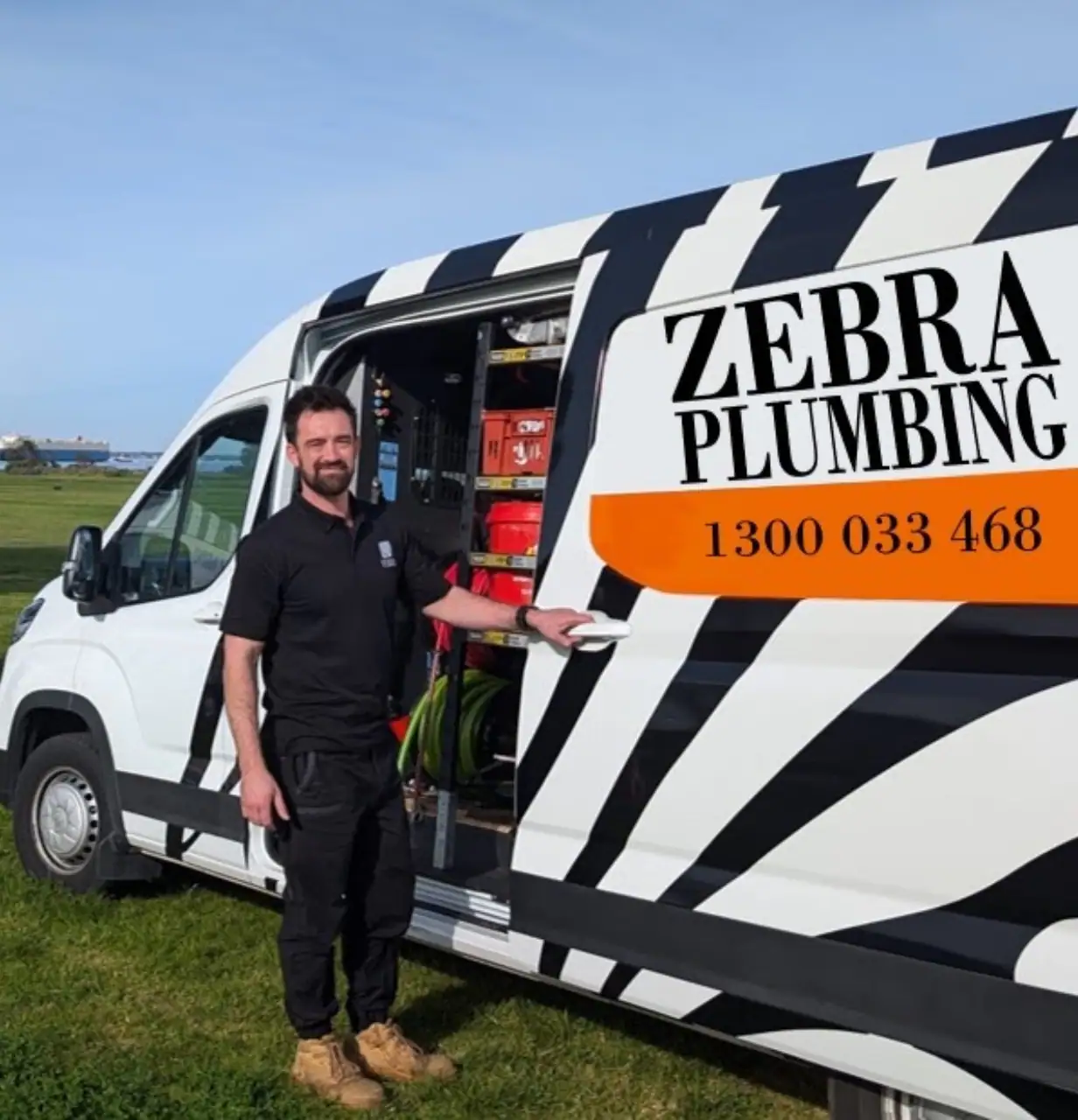 Byron standing in front of a white Zebra Plumbing-branded van