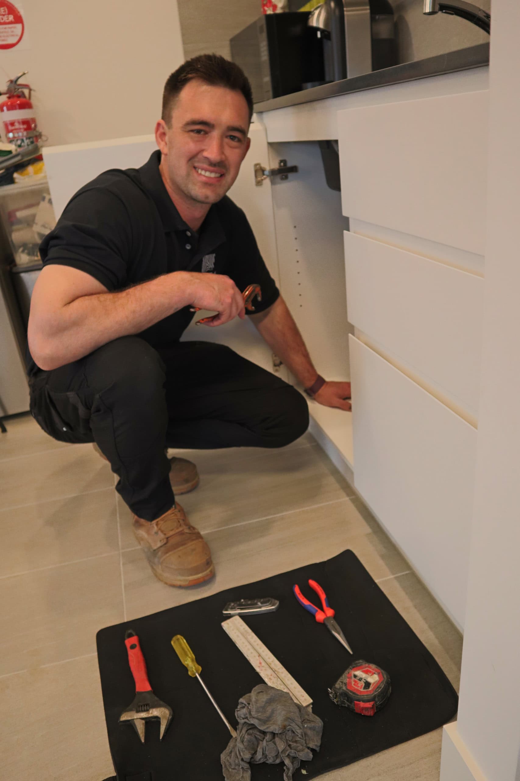 A smiling plumber with tools laid out in a tidy arrangement in a modern home.