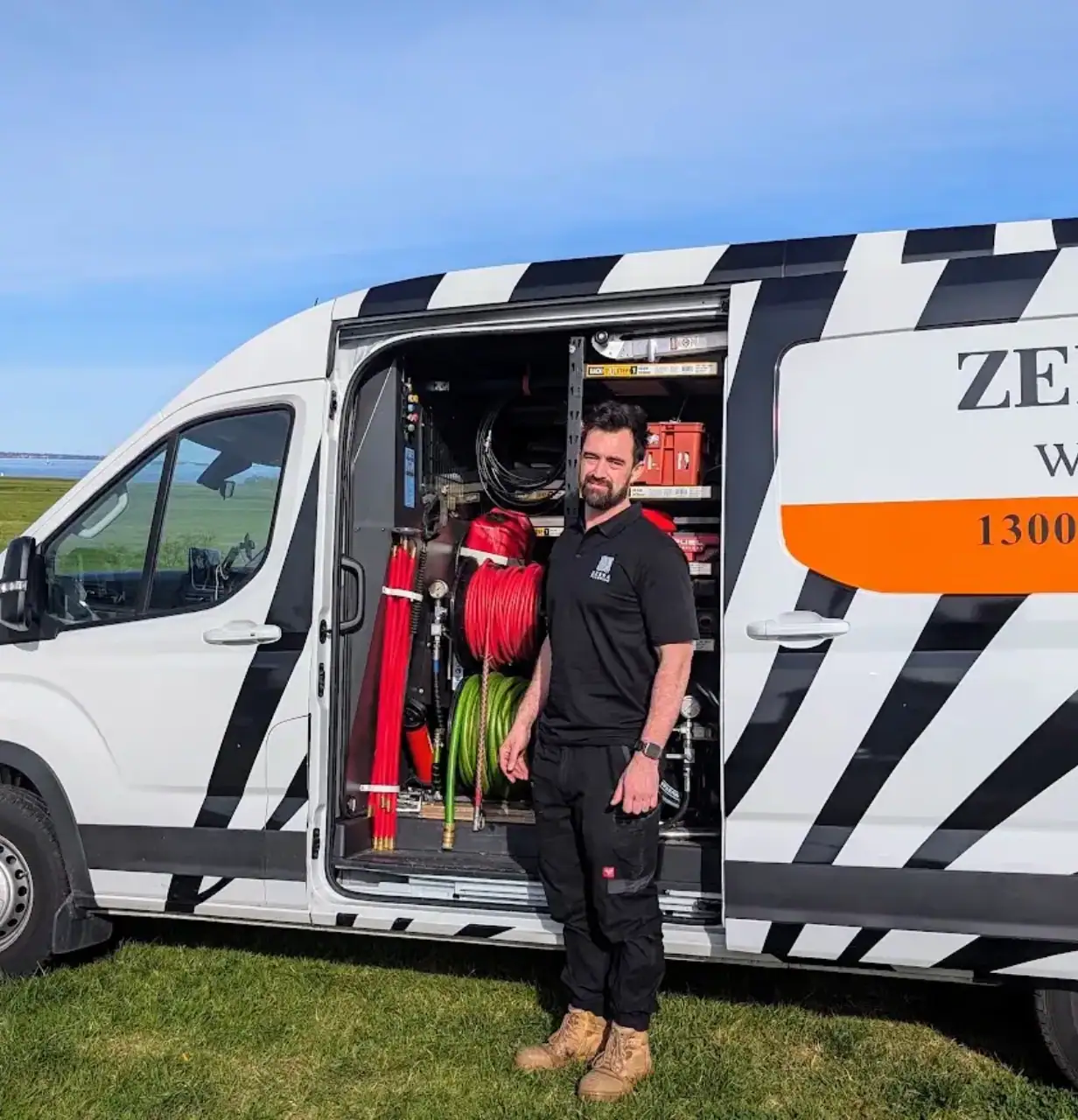 A Zebra Plumbing staff member standing beside a fully stocked van.